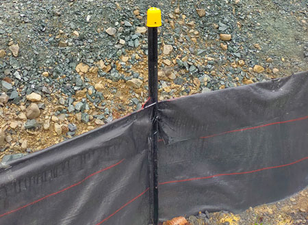 Black woven silt fence attached to Waratah and safety cap stopping sediment runoff.