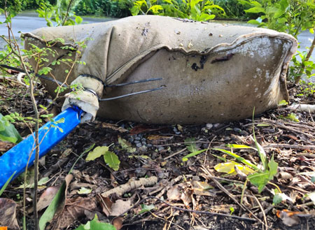 Leaves and dirt around a dewatering bag filled with dirt and silt