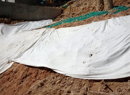Civil control geotextiles placed on a dirt hill pinned in place with steel ground pins. Promoting vegetation